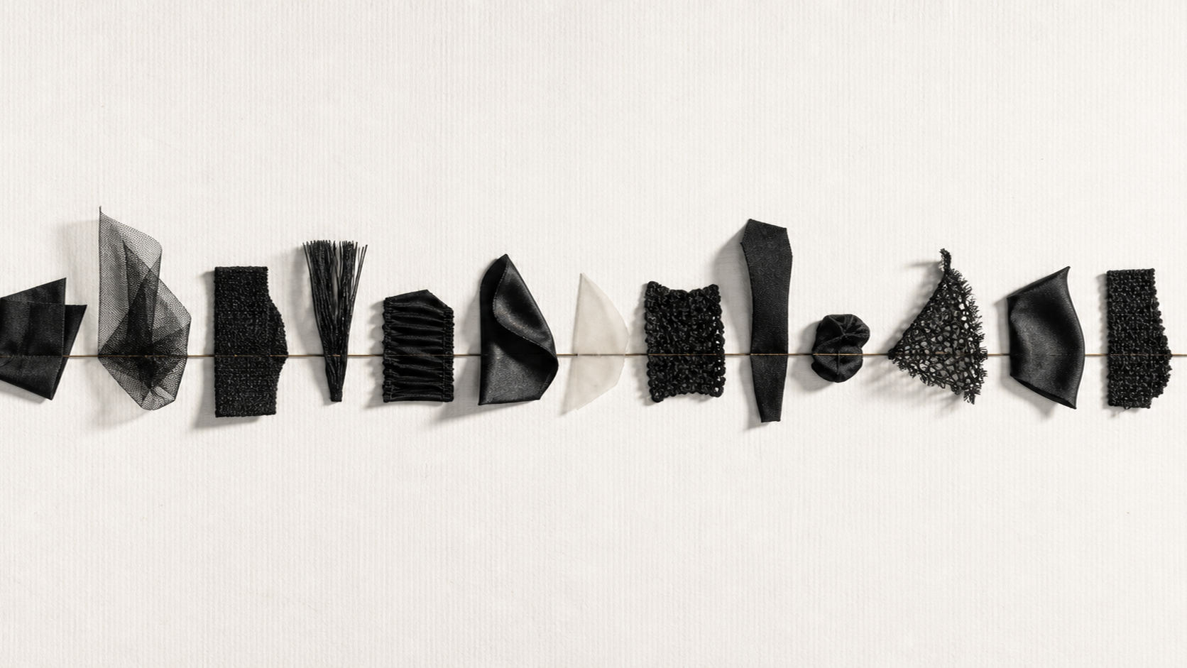 Fifteen textile forms aligned around one bronze axis