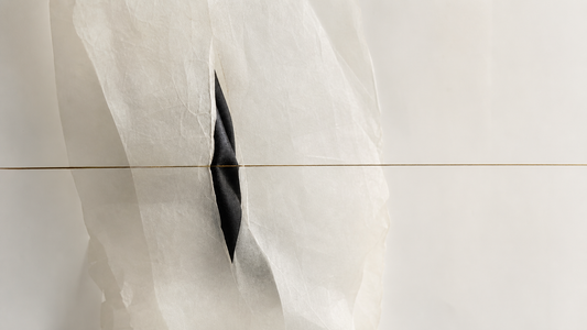 Translucent vellum and black textile moving around a bronze hairline