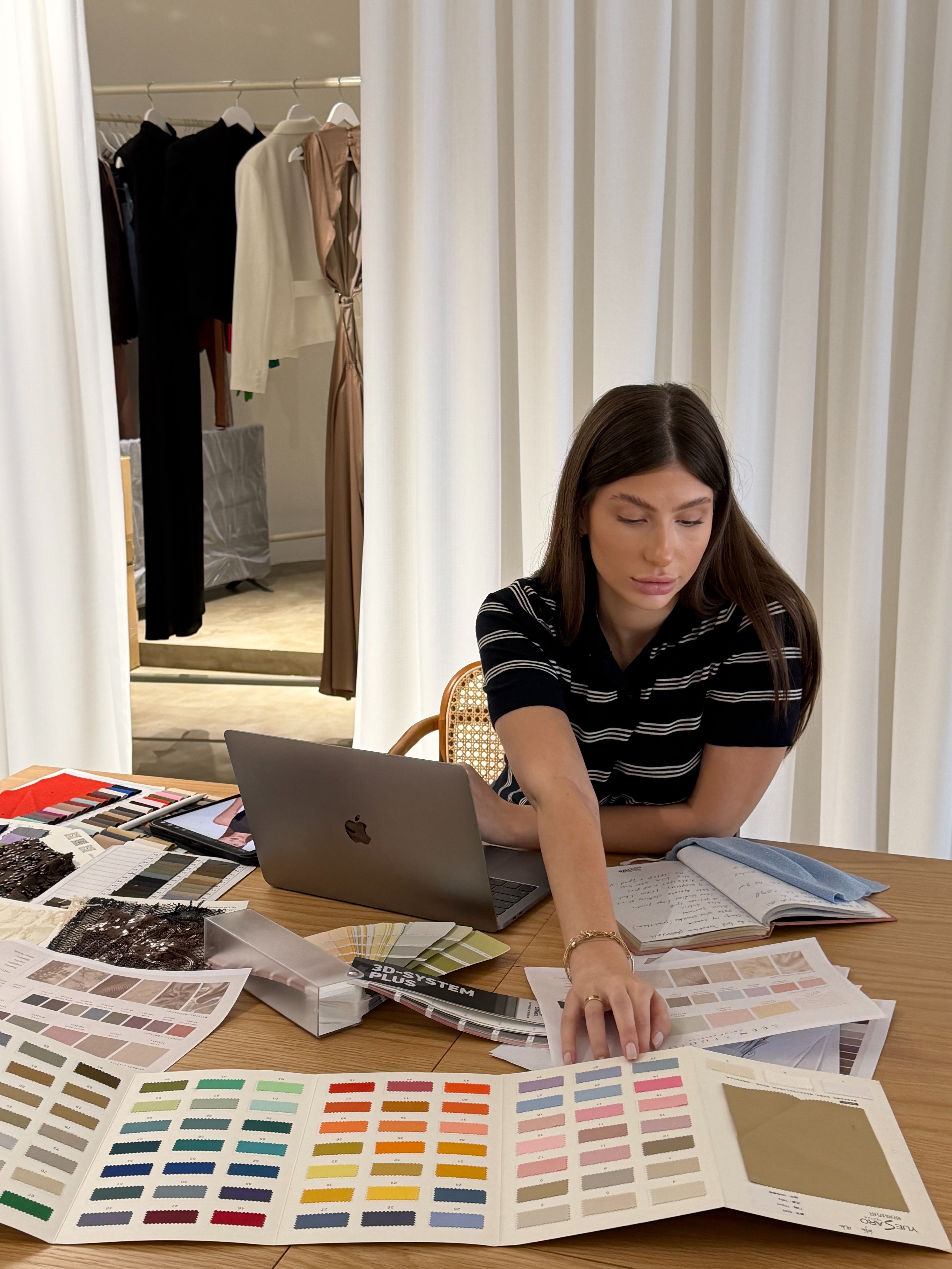 Nini working among sketches, samples, and colour palettes
