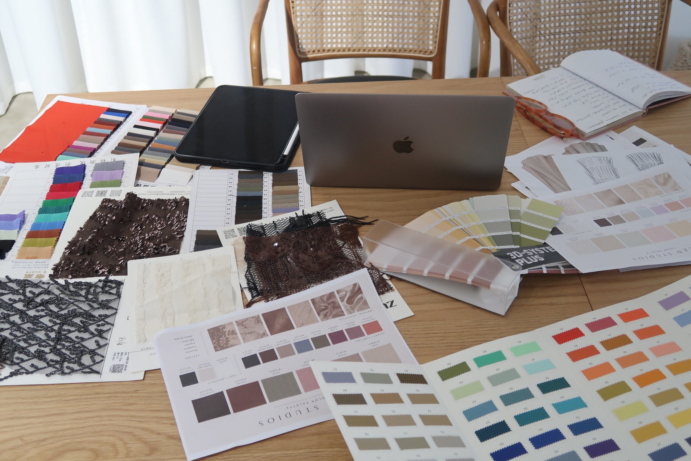Materials, colour swatches, sketches and a laptop spread across the Seen Studios worktable