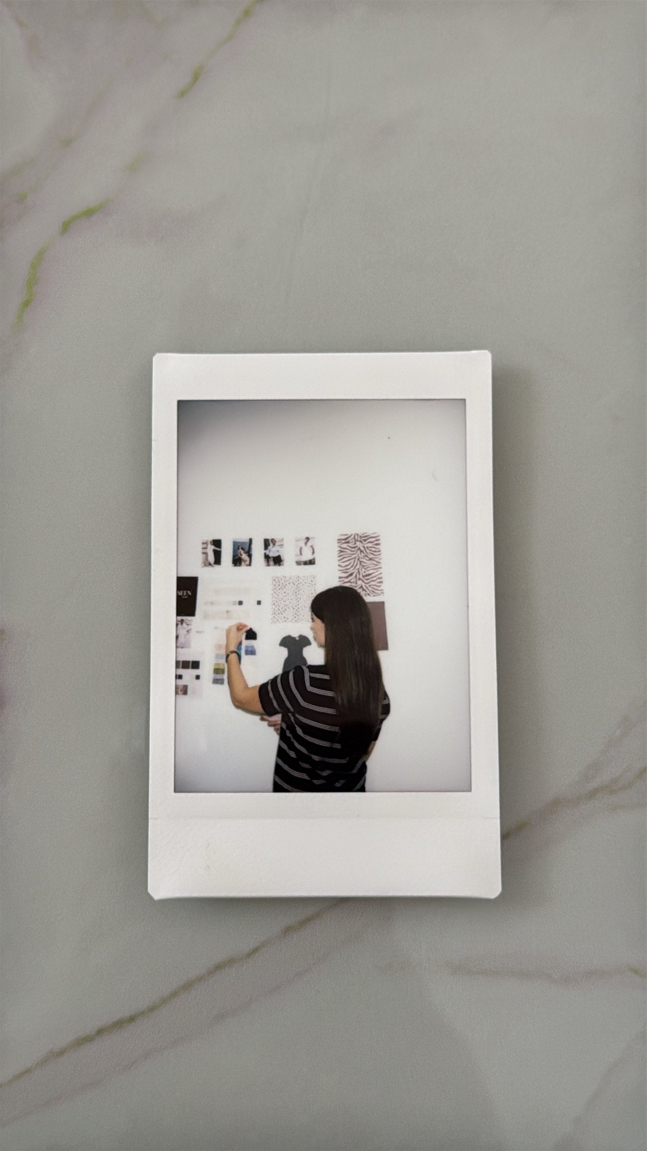 Nini building a moodboard on the Seen Studios studio wall, photographed as a Polaroid